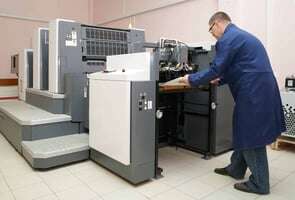 Homem segurando papel saindo de máquina de impressão digital